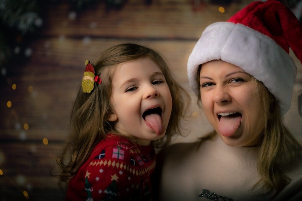 Mother and daughter Christmas clothing poking out tongues